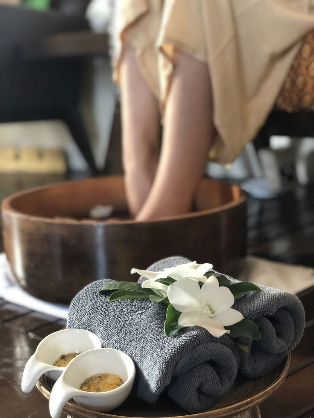 Feet soaking in a wooden bowl with flowers
